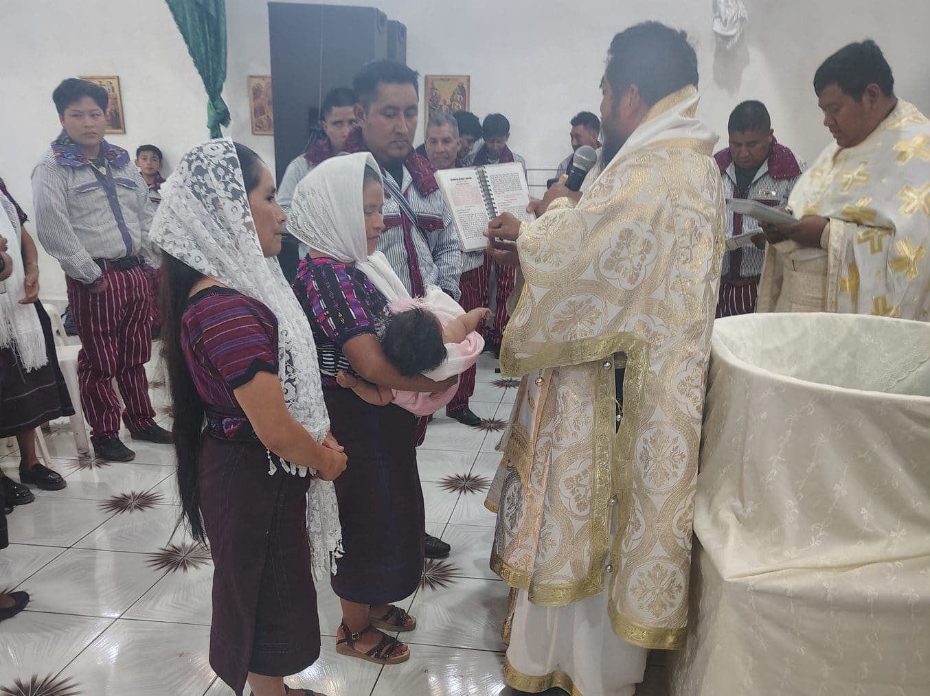 A priest baptizing an infant held by its mother